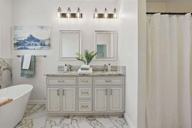 full bathroom with marble finish floor, a freestanding bath, a sink, and double vanity