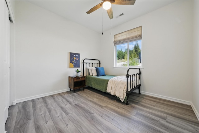 bedroom featuring baseboards, wood finished floors, visible vents, and ceiling fan