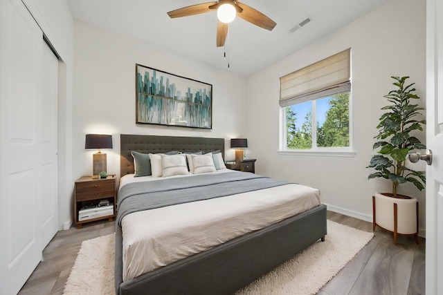 bedroom with light wood-style flooring, baseboards, visible vents, a ceiling fan, and a closet