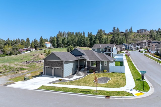 ranch-style home with a front lawn, driveway, an attached garage, fence, and a residential view
