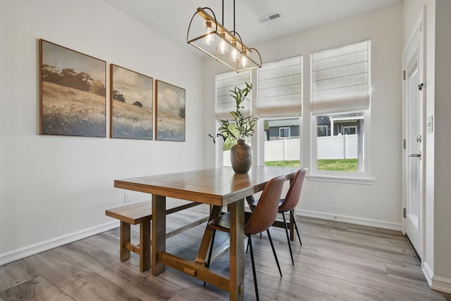 dining room with light wood finished floors, baseboards, and visible vents