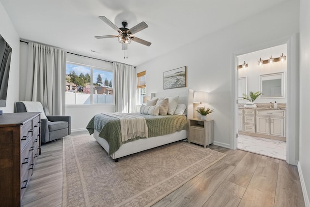 bedroom with a sink, light wood-type flooring, ensuite bath, baseboards, and ceiling fan