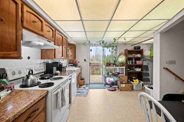 kitchen with white appliances, a drop ceiling, under cabinet range hood, brown cabinets, and a sink