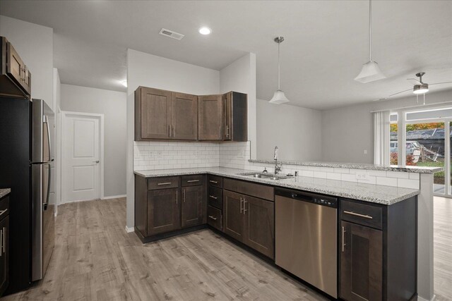 kitchen featuring stainless steel appliances, backsplash, a sink, visible vents, and a peninsula