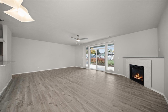 unfurnished living room with a fireplace, wood finished floors, ceiling fan, and baseboards