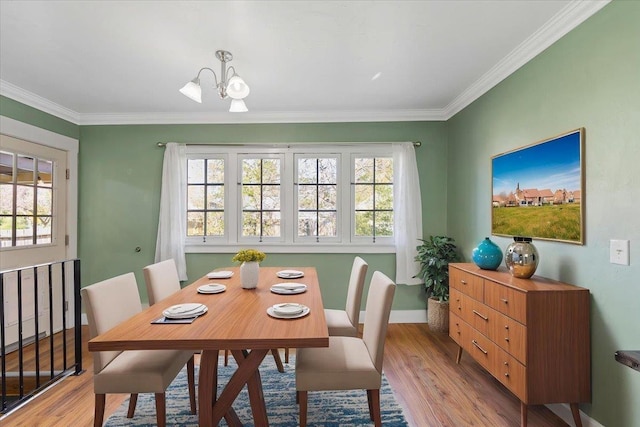 dining area featuring crown molding, a chandelier, and light wood-type flooring