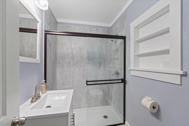 bathroom with built in shelves, a shower stall, crown molding, and vanity