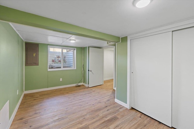 below grade area featuring electric panel, light wood finished floors, and baseboards