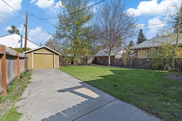 view of yard featuring an outbuilding, a detached garage, driveway, and a fenced backyard