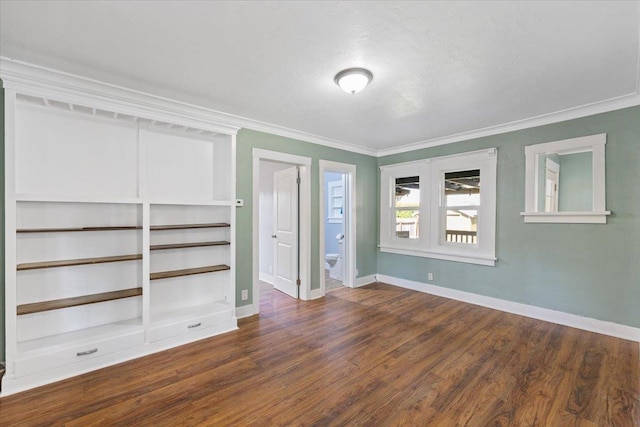 unfurnished bedroom with crown molding, ensuite bathroom, dark wood-style flooring, and baseboards