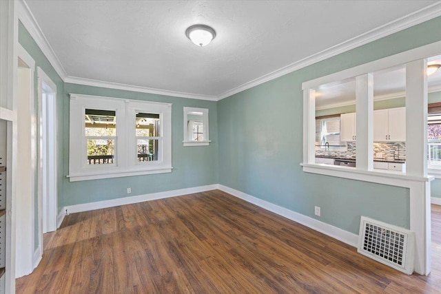 empty room featuring dark wood finished floors, visible vents, and a wealth of natural light