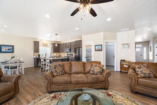 living area with dark wood-style flooring, ceiling fan, recessed lighting, and visible vents