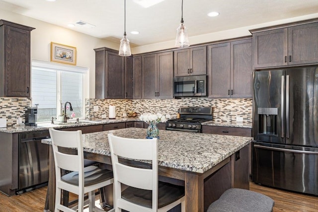 kitchen featuring dark brown cabinetry, light stone countertops, appliances with stainless steel finishes, a sink, and visible vents