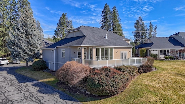 back of property featuring a yard, a shingled roof, and stucco siding
