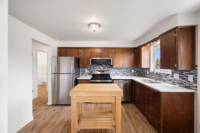kitchen with backsplash, a sink, appliances with stainless steel finishes, and light countertops