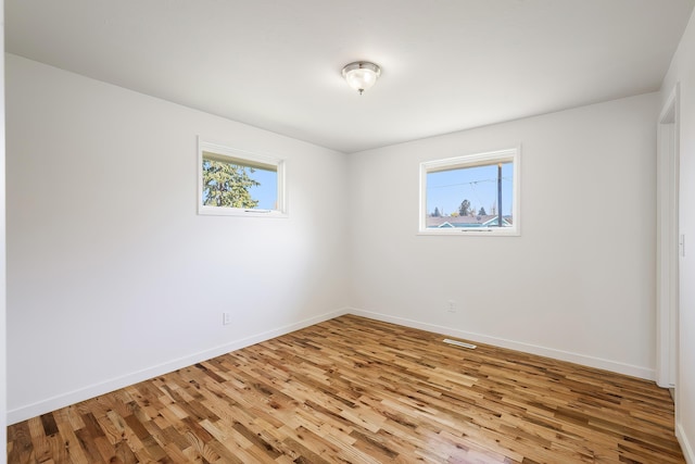 spare room featuring baseboards, visible vents, and wood finished floors