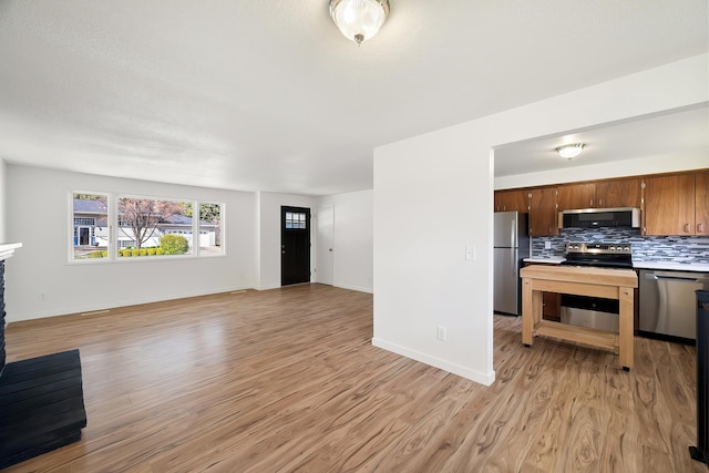 11904 E 22nd Ave, Spokane Valley, WA 99206 - kitchen featuring stainless steel appliances, light wood finished floors, open floor plan, tasteful backsplash, and light countertops