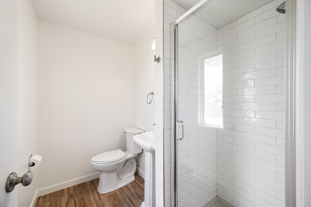 full bath with baseboards, wood finished floors, a shower stall, and toilet