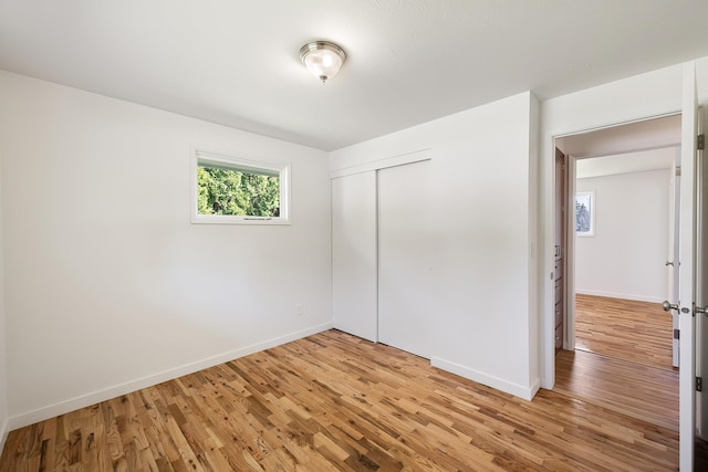 unfurnished bedroom with baseboards, light wood-style floors, and a closet
