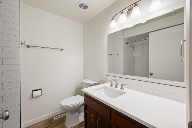 bathroom with toilet, visible vents, a shower, baseboards, and wood finished floors