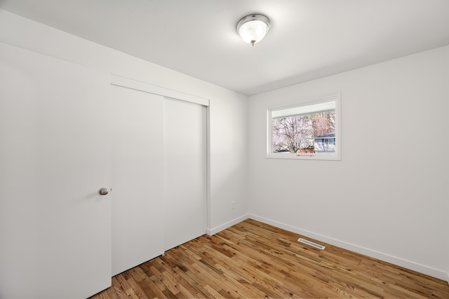 unfurnished bedroom with light wood finished floors, a closet, visible vents, and baseboards