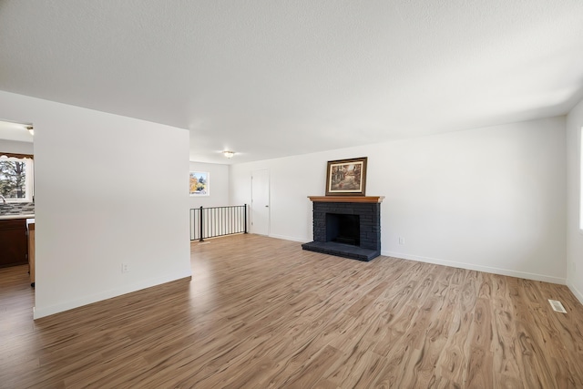unfurnished living room featuring baseboards, light wood-style floors, and a healthy amount of sunlight