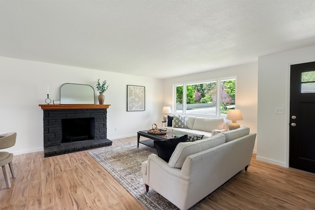 11904 E 22nd Ave, Spokane Valley, WA 99206 - living area with wood finished floors, a stone fireplace, baseboards, and a textured ceiling