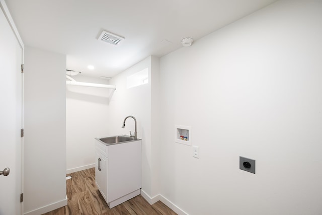 washroom featuring hookup for an electric dryer, washer hookup, a sink, light wood finished floors, and cabinet space