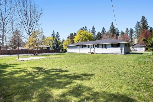 rear view of house with fence and a yard