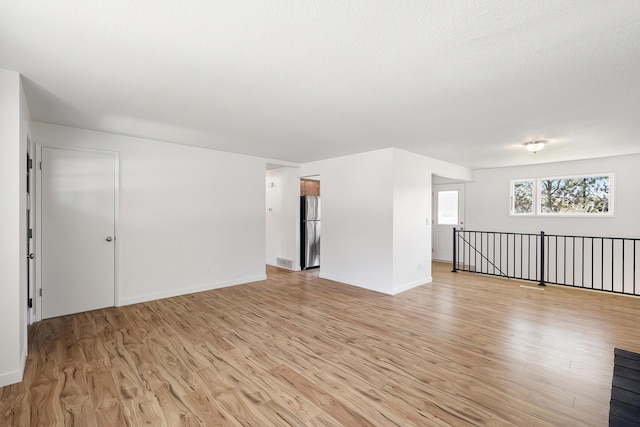 unfurnished living room featuring visible vents, baseboards, and light wood-style floors