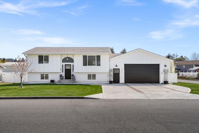 raised ranch featuring a garage, board and batten siding, a front yard, and driveway