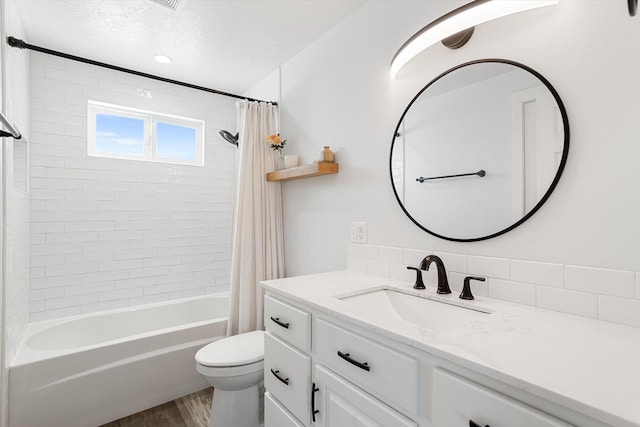 bathroom featuring wood finished floors, shower / bathtub combination with curtain, toilet, vanity, and a textured ceiling