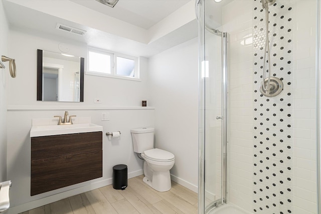 bathroom with wood finished floors, toilet, vanity, visible vents, and a stall shower