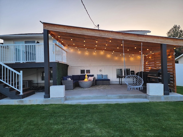 back of property at dusk with a patio, an outdoor living space, stairway, and a yard
