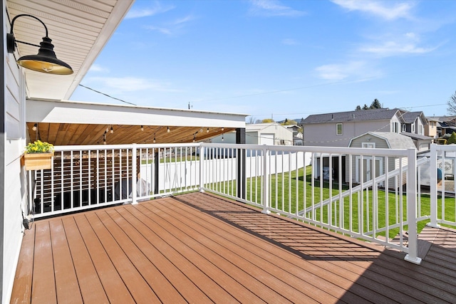 deck featuring a residential view, a lawn, an outdoor structure, and a storage shed