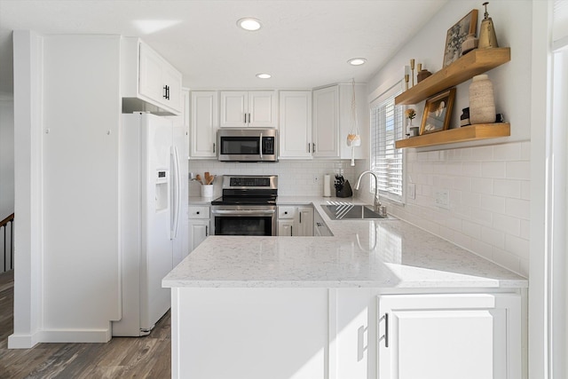 kitchen featuring white cabinetry, open shelves, a sink, stainless steel appliances, and wood finished floors