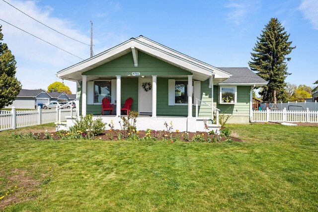 bungalow-style house featuring covered porch, fence, and a front yard