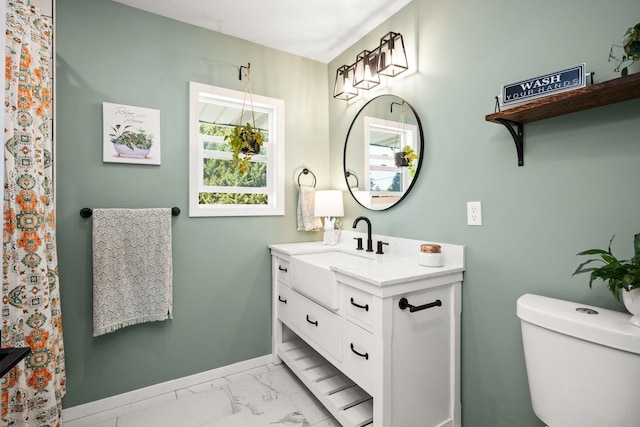 bathroom featuring toilet, marble finish floor, vanity, and baseboards