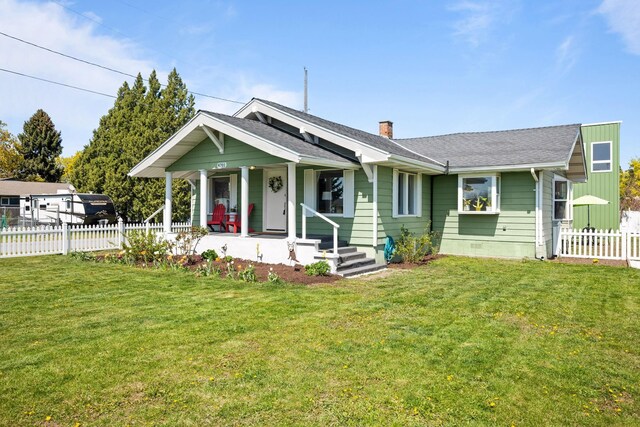 view of front of home featuring fence, covered porch, a front yard, and a chimney