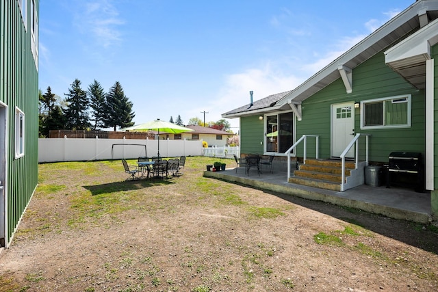 view of yard with outdoor dining space, a patio area, entry steps, and a fenced backyard