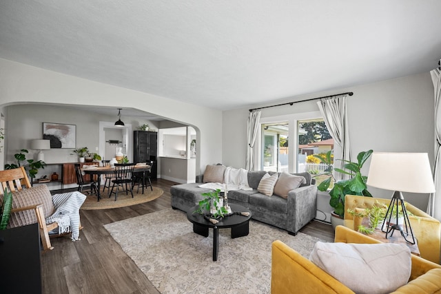 living room featuring arched walkways and wood finished floors