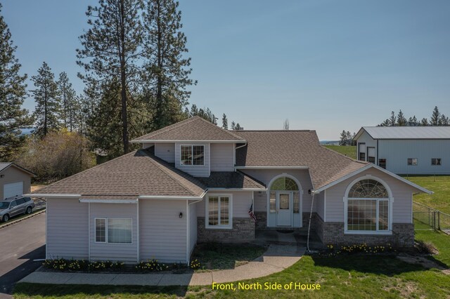 view of front of property with brick siding, fence, a front lawn, and roof with shingles