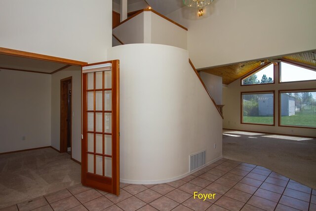staircase featuring visible vents, baseboards, carpet, high vaulted ceiling, and tile patterned flooring
