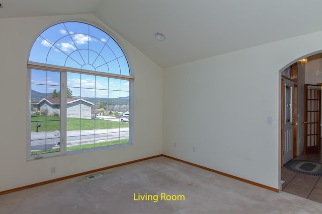carpeted empty room with arched walkways, visible vents, lofted ceiling, and baseboards