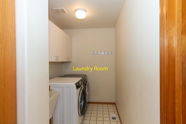 washroom featuring baseboards, visible vents, washer and dryer, and cabinet space
