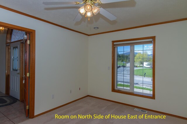 spare room featuring crown molding, a ceiling fan, visible vents, baseboards, and light colored carpet