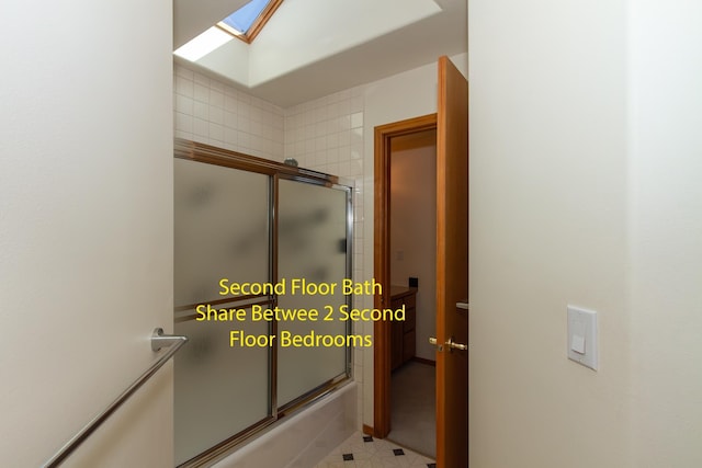 bathroom with a skylight and bath / shower combo with glass door