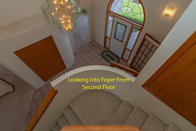 entrance foyer featuring an inviting chandelier, visible vents, and stairs
