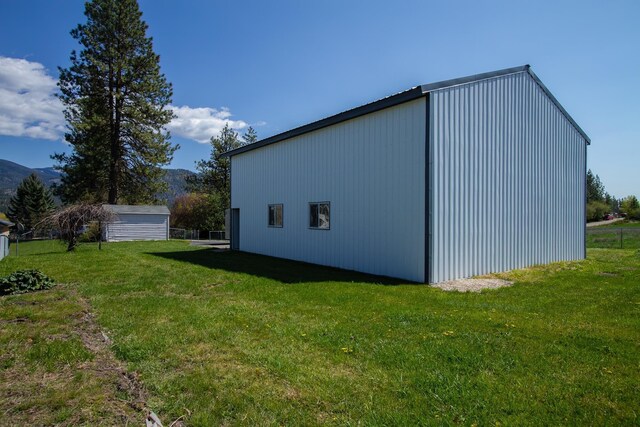 view of side of property featuring a lawn, an outdoor structure, and an outbuilding