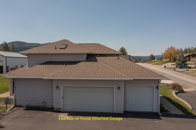 exterior space featuring fence, aphalt driveway, and roof with shingles
